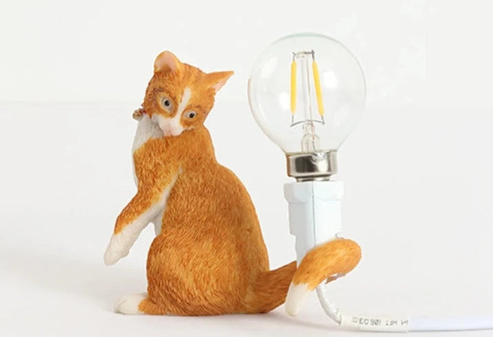 Resin cat holding bulb table lamp for bedroom decor.