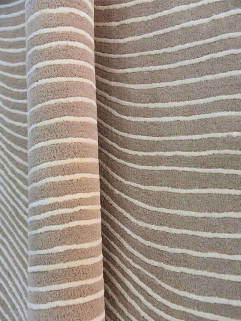 Oval beige rug with white wavy line pattern and luxury texture.