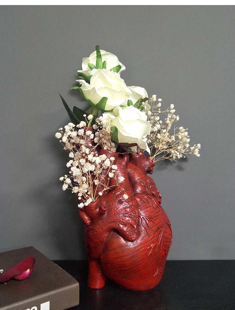 Red anatomical heart-shaped vase for floral arrangement.