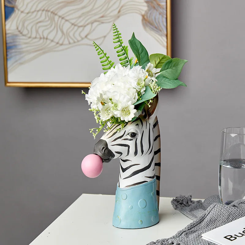 Creative zebra sculpture vase holding artificial stems on console.