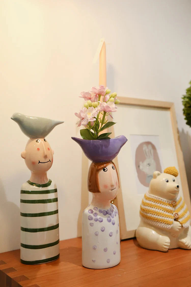 Whimsical ceramic couple vases with floral arrangement.
