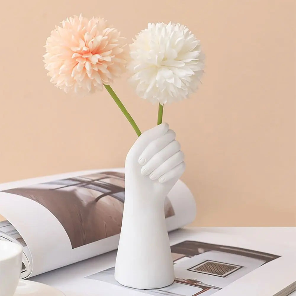 Modern white resin hand-shaped vase holding flowers.