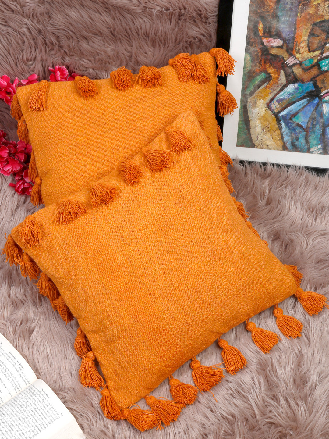 Handwoven orange cotton pillow covers with tassel detailing.