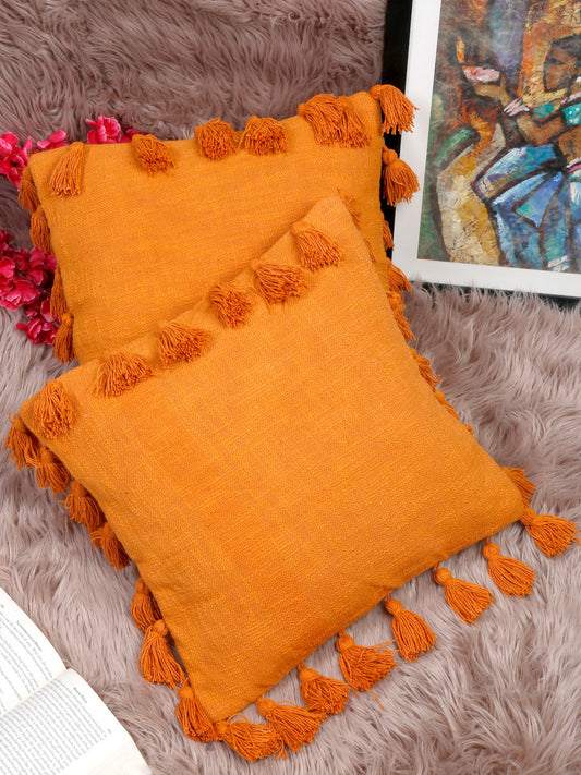 Handwoven orange cotton pillow covers with tassel detailing.