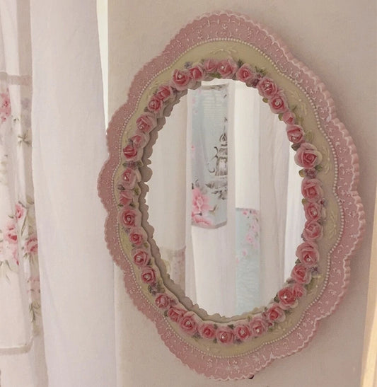 Ornate floral design oval mirror with pastel pink finish.